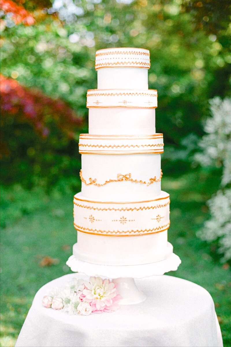 4-tiered pastel wedding cake with gold piping and bows