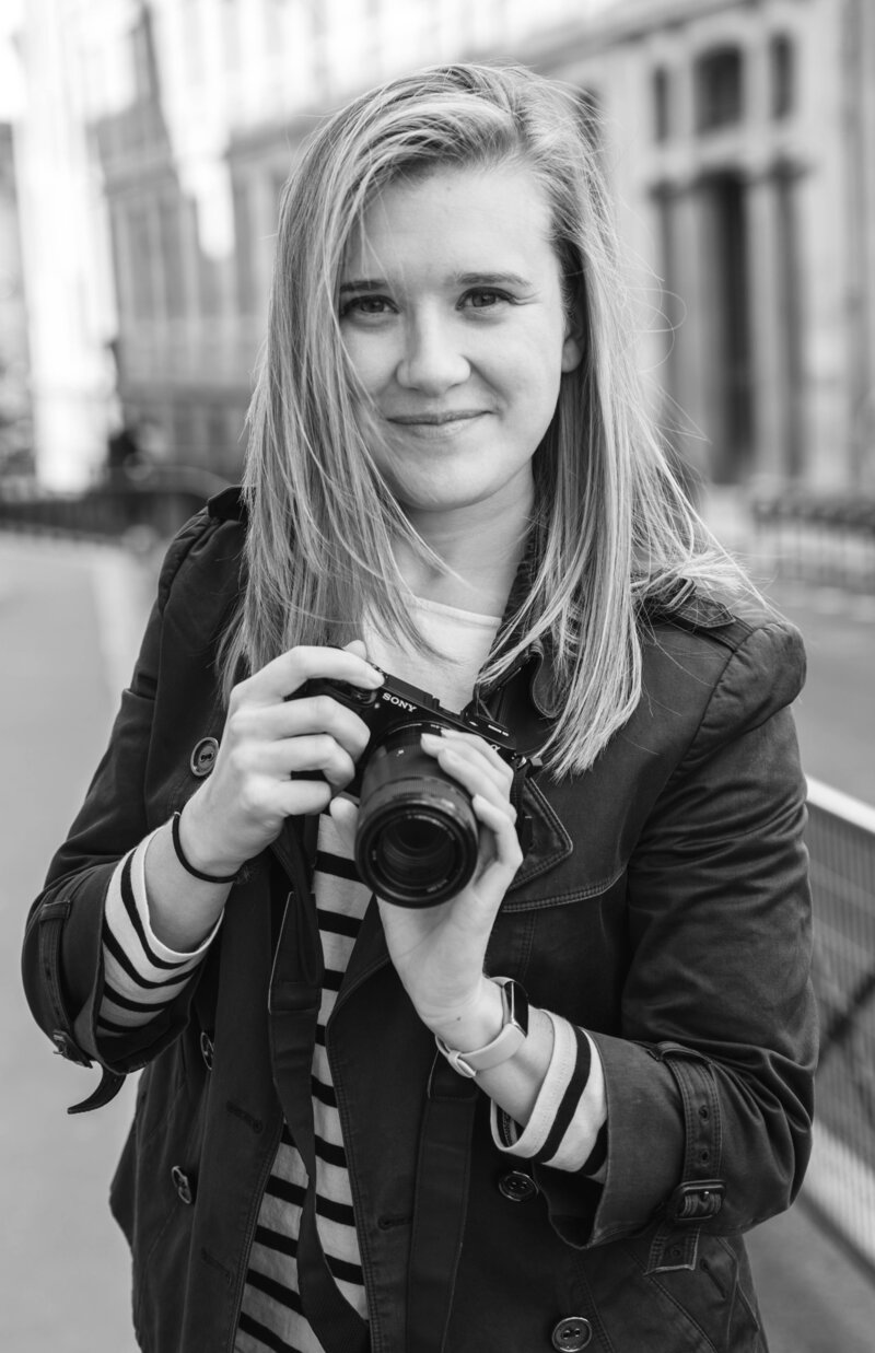 Kara Ferguson owner of Round Our World posing with a camera in Paris France