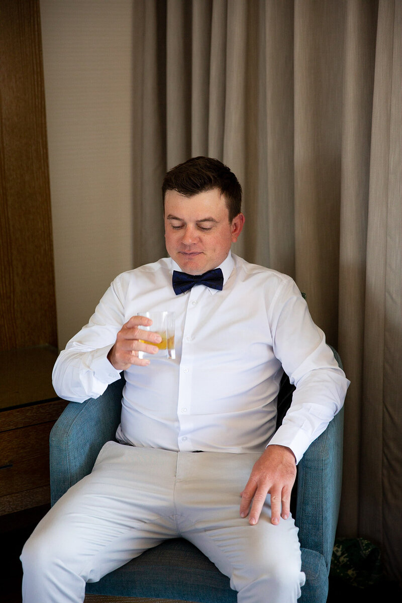 Groom sits and with champagne on his hand