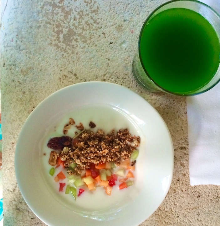 Yogurt bowl with granola and fresh fruit with a glass of green juice