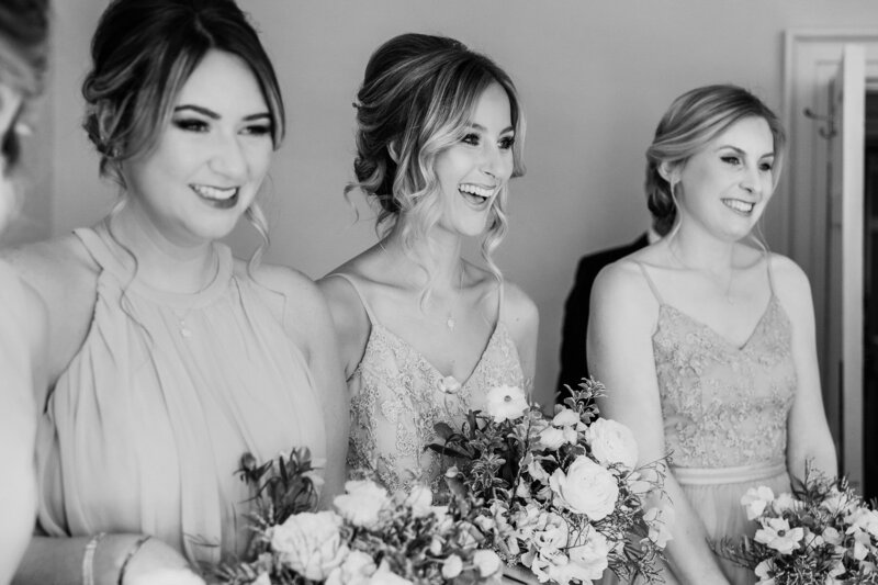 Bridesmaids smiling at bride