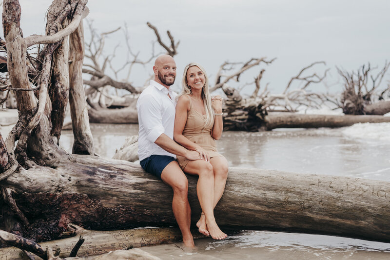 couple sitting on driftwood on hunting island