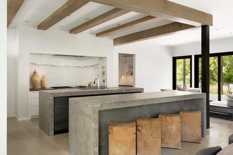 Dual concrete islands with waterfall edges and raw timber ceilings
