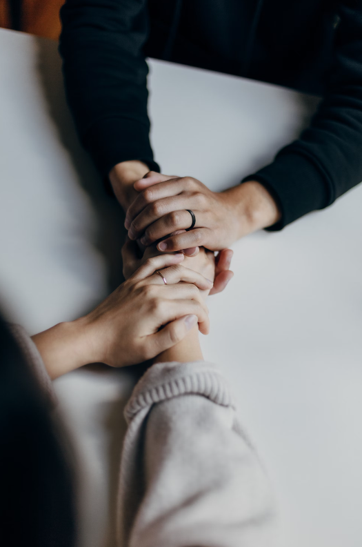 Two people holding hands providing support