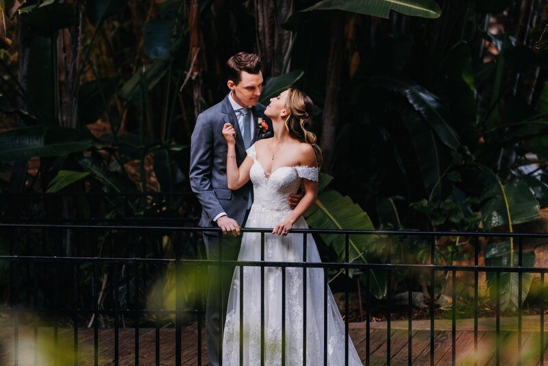 Bride and groom in an embrace on the dock surrounded by greenery at Grand Tradition Estate and Gardens wedding venue in San Diego.