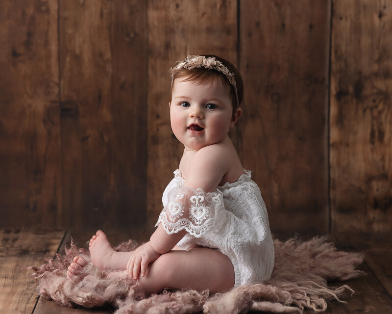 Pittsburgh Photographer baby sitting on pink rug wearing a floral headband