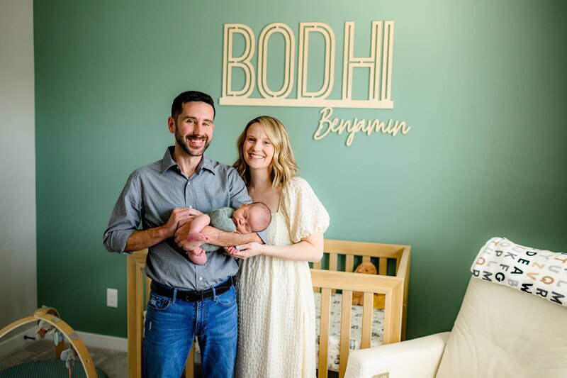 mother and father standing in newborn nursery holding their newborn son