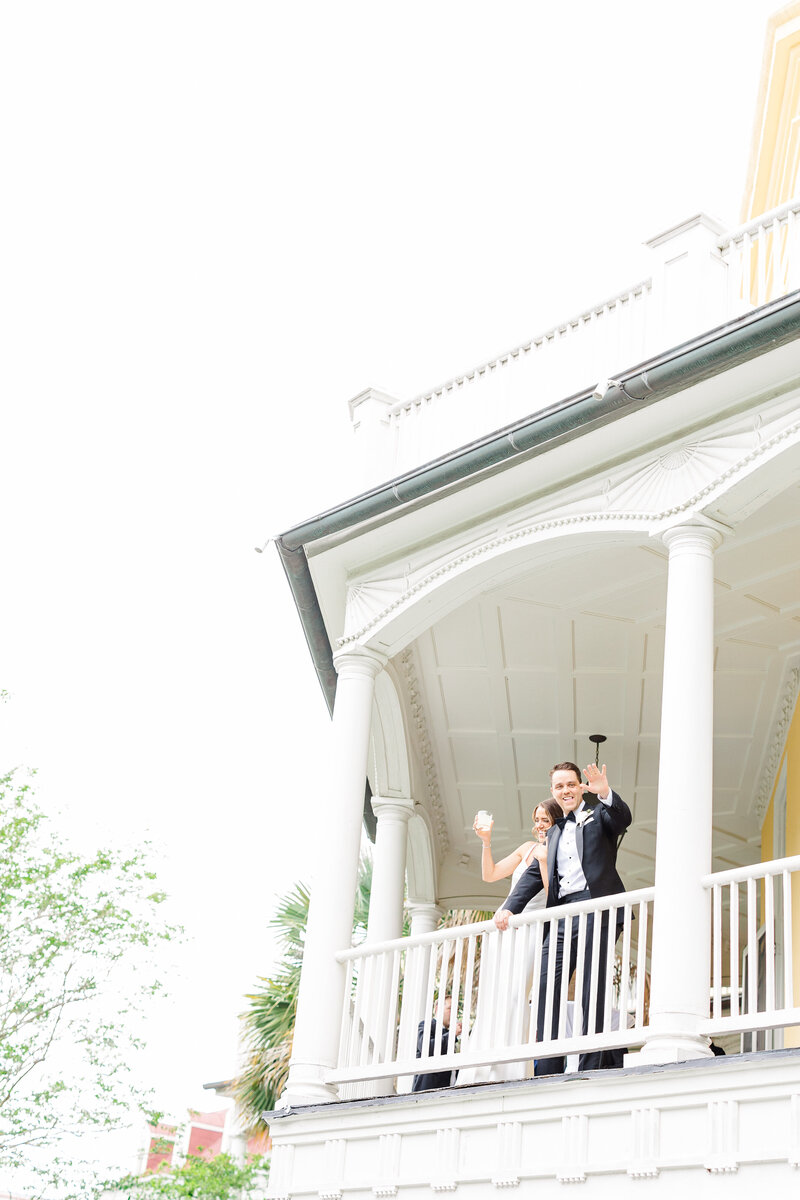 bride and groom waving off balcony at the william aiken house
