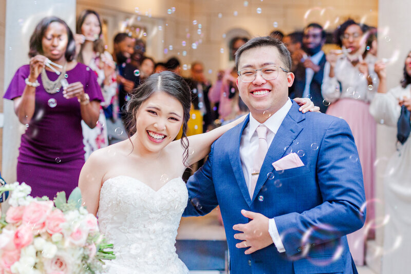 An Asian-American couple smile as they leave their wedding in a bubble exit at the Wimbish House in Atlanta Georgia.