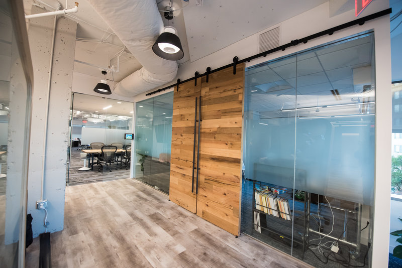 Wooden doors open conference room with glass walls.