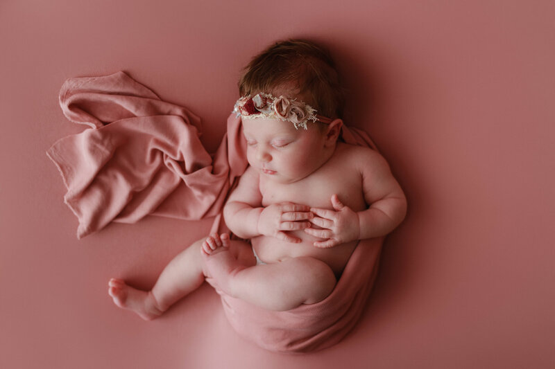 pretty newborn baby sleeping with pink bow and pink backdrop