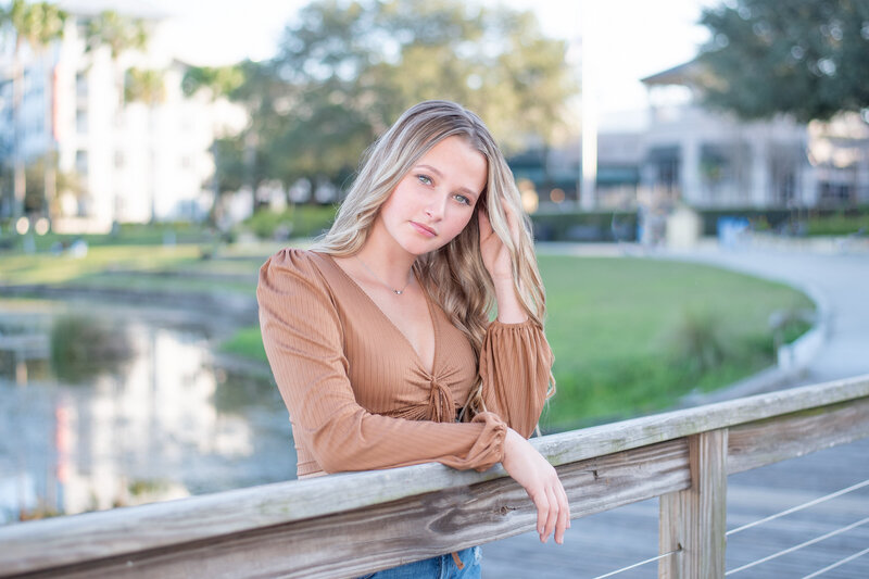A senior girl from Hagerty High School leaning on a rail at a senior shoot with Khim Higgins Photography.