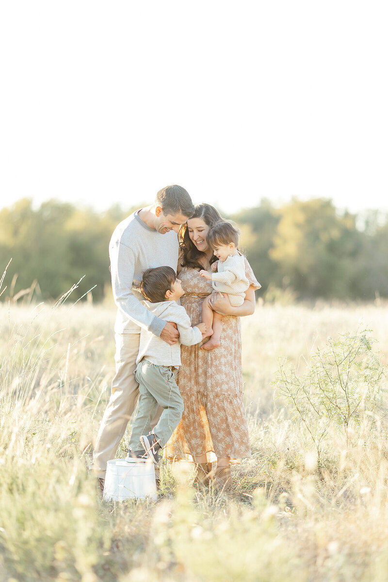 A young family of 4 portrait taken while they are playing in a field at a local Dallas Texas park taken by a DFW Family Photographer.