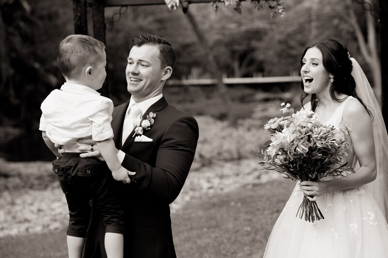 Bride and groom enjoy playing with their son on wedding day