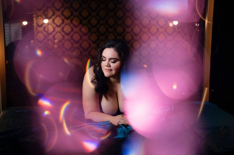 Curvy woman posing on bed with light flares in the foreground