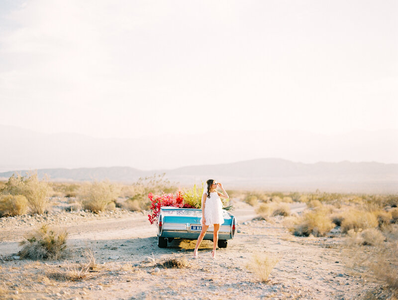 woman in the desert with blue convertible car