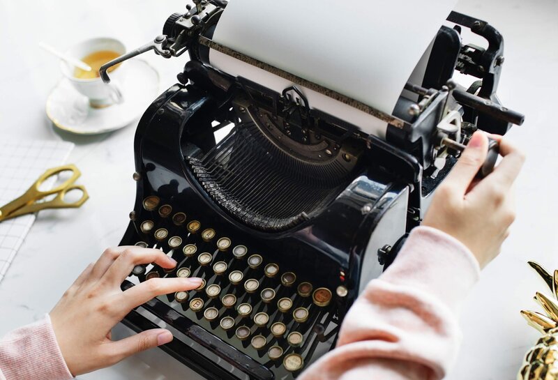 Old fashioned typewriter with woman typing on it