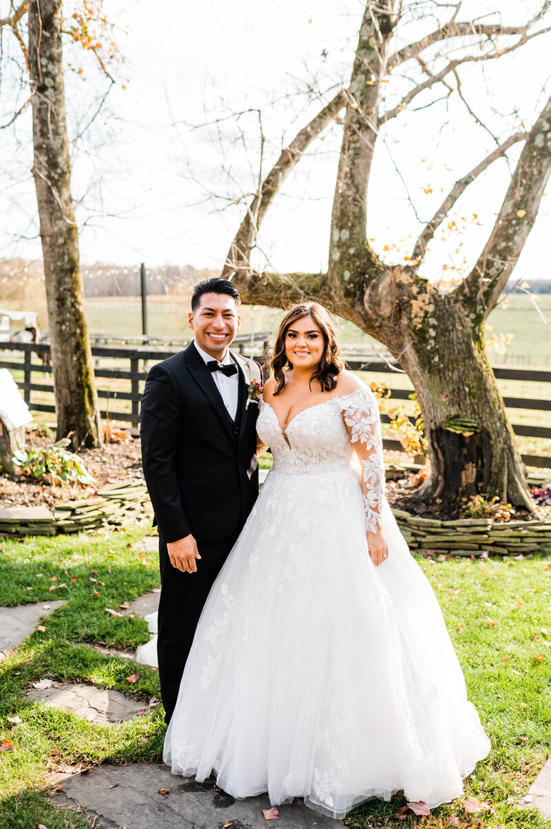 garden wedding venue for a Shenandoah wedding with bride and groom standing together on a stone path and smiling with trees and flowers behind them captured by charlottesville wedding photographer