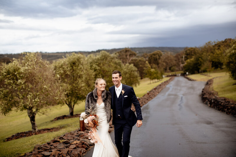 Bride and Groom walks down the wet road