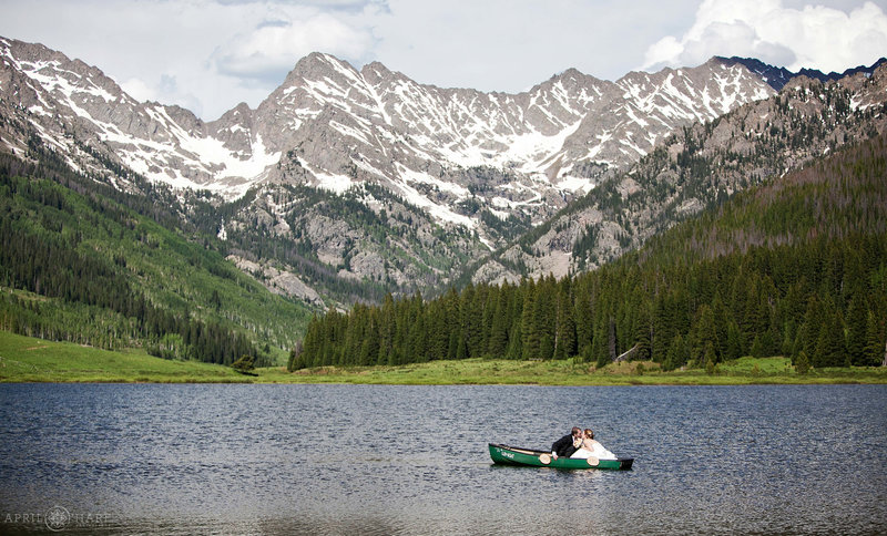 Bride and Groom kiss in the canoe with stunning mountain views at Piney Lake