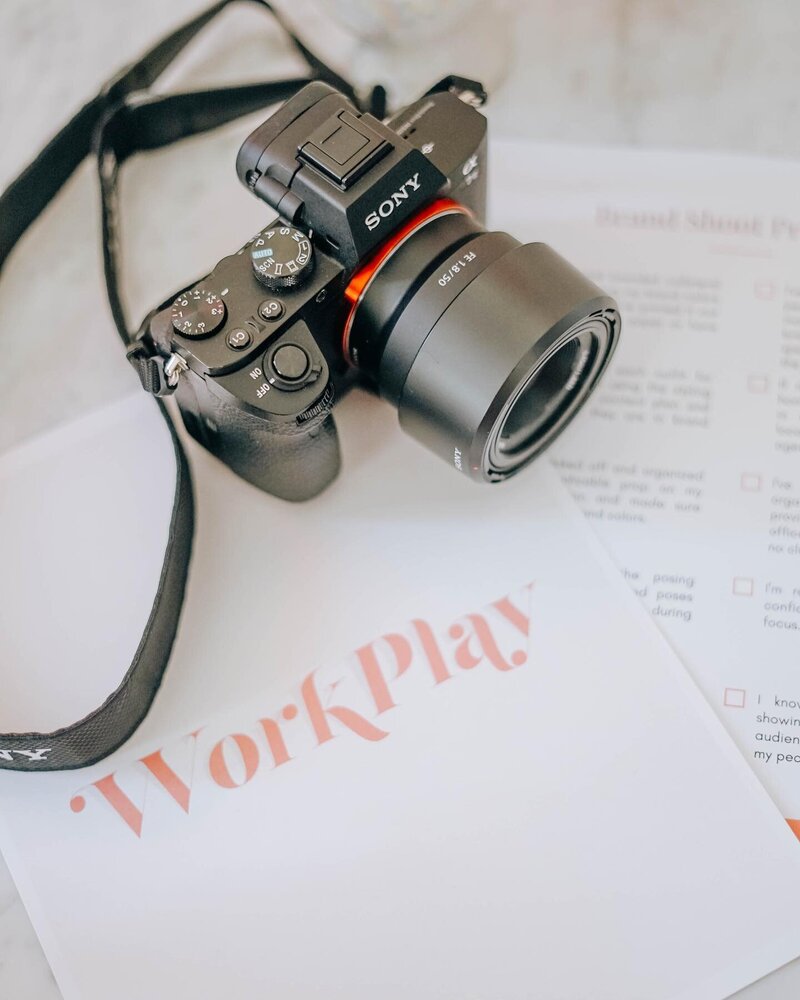 DSLR camera sitting on white workbook with client logo on the cover