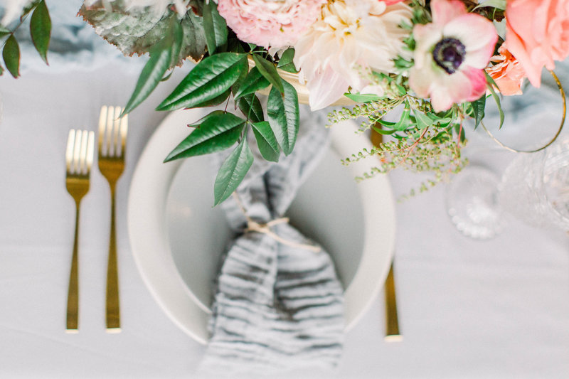 plate and gold forks laying on  table with flowers