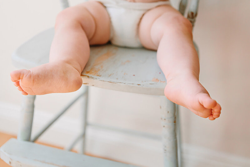 Photo of a baby's feet and legs sitting in a light blue vintage high chair