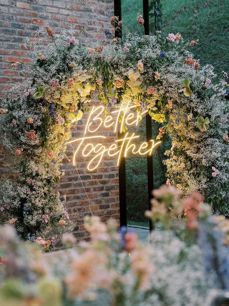 Floral arch at the reception with the neon sign that says Better Together.