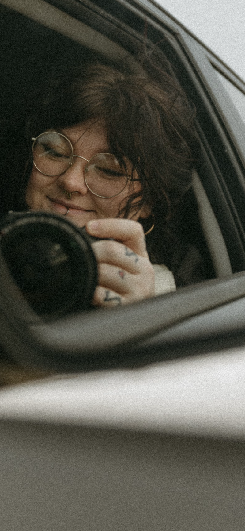 Photographer taking a self portrait in the car mirror while her hair flows in the wind