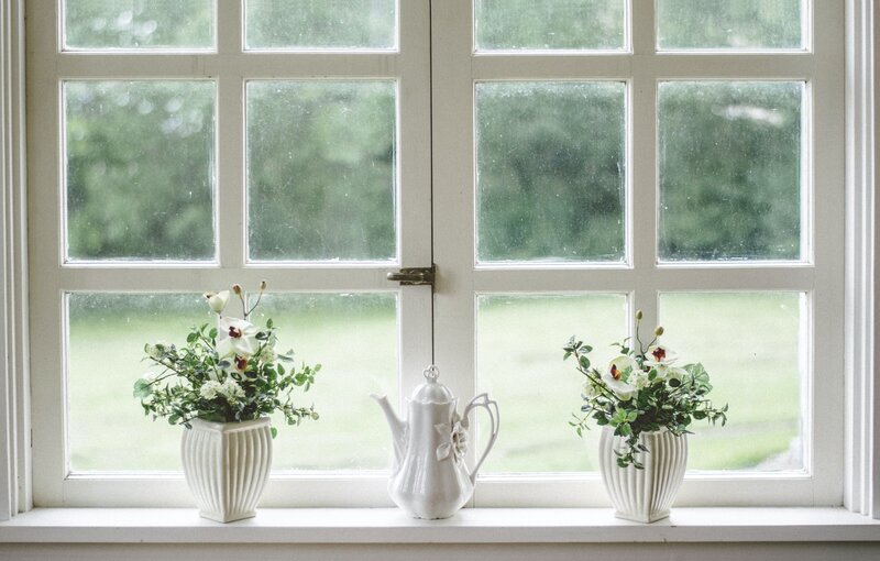 White planters and a teapot sitting in front of a window in an old home.
