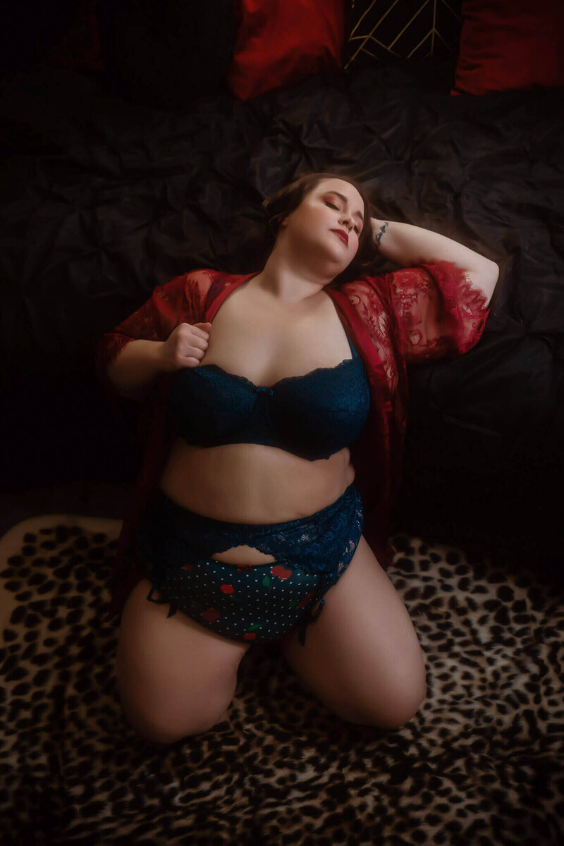 Woman in blue and cherry print lingerie on a leopard rug in her Dallas boudoir session.