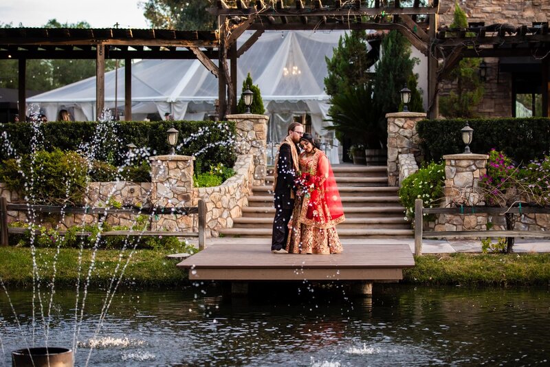 Bride and groom in Indian wedding attire embracing on the dock of the lake at Lake Oak Meadows wedding venue in Temecula.