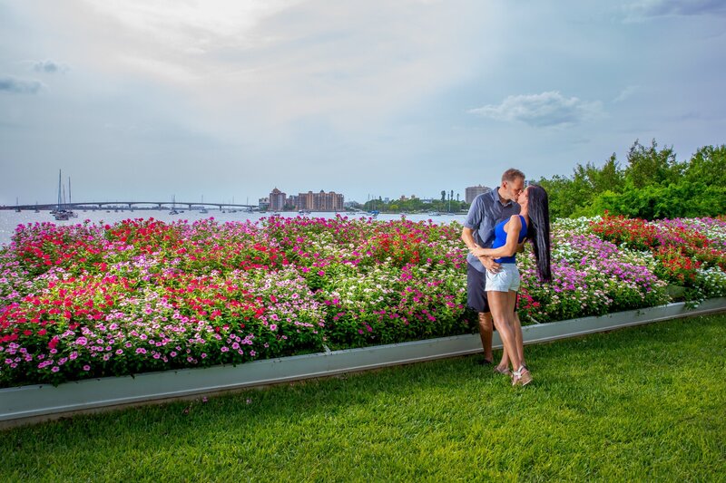 wide angle of engaged couple with flowers and downtown Sarasota in the background