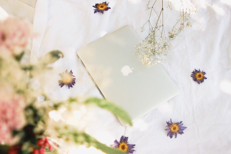 macbook air flat lay on a sheet surrounded by blue lotus flowers