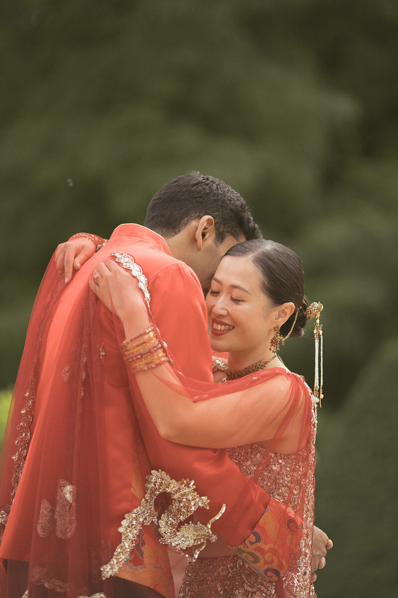 Interracial Asian couple embracing each other joyfully at their Cornwall Manor wedding.