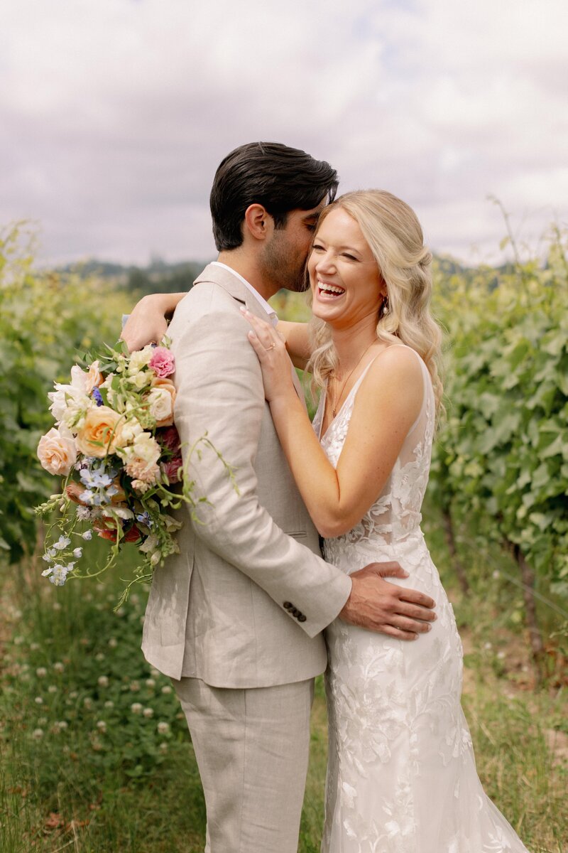 Bride & Groom Embracing in Vineyard with Bouquet - Marilee & Andrew | Bright & Colorful At the Joy Salem Oregon Wedding