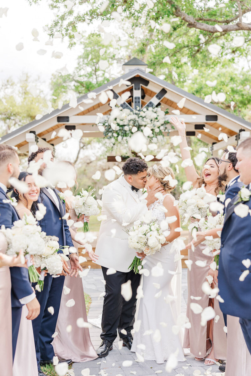 bride and groom kissing as guests celebrate