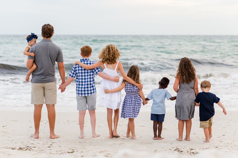 Pensacola Beach Family Photographer, Jennifer Beal Photography  extended family session at Navarre Bbeach. Cousins hugging each other looking out over waves.