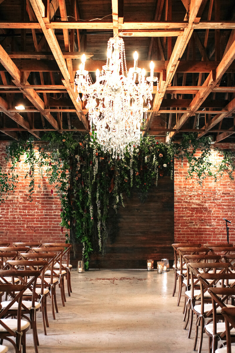 Hanging chandeliers, exposed brick walls and  hanging greenery and florals for industrial chic wedding ceremony at the St Vrain