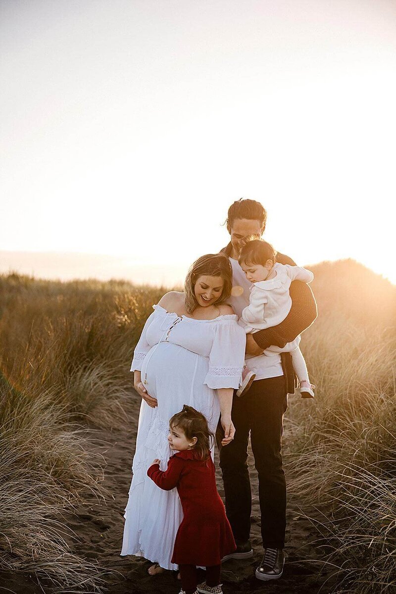 A family of four being photographed during sunset at a new plymouth beach by aimee kelly photography
