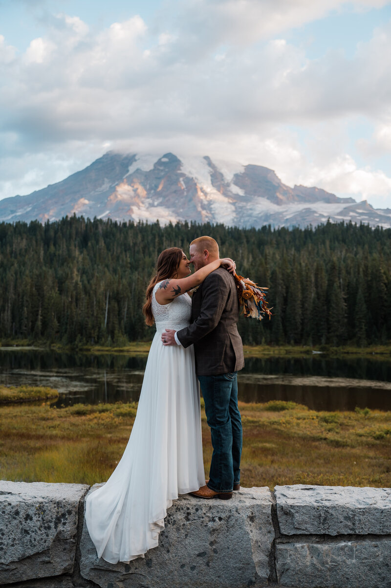 Bride and groom smiling at each other on their elopement day with views of Mount Rainier in the background