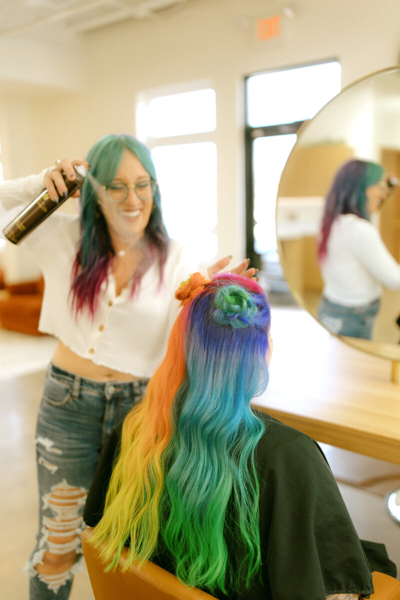 Woman with brightly colored hair getting hair sprayed