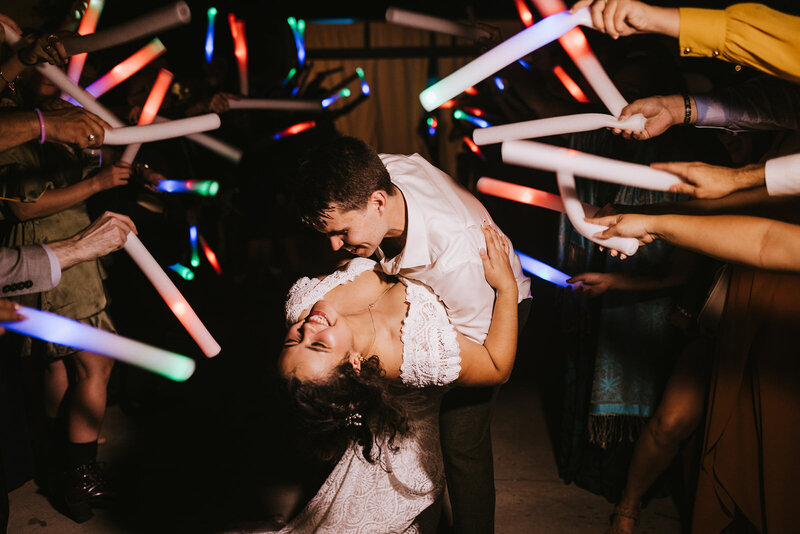elated couple ending their LED Baton send off with the groom dipping his bride