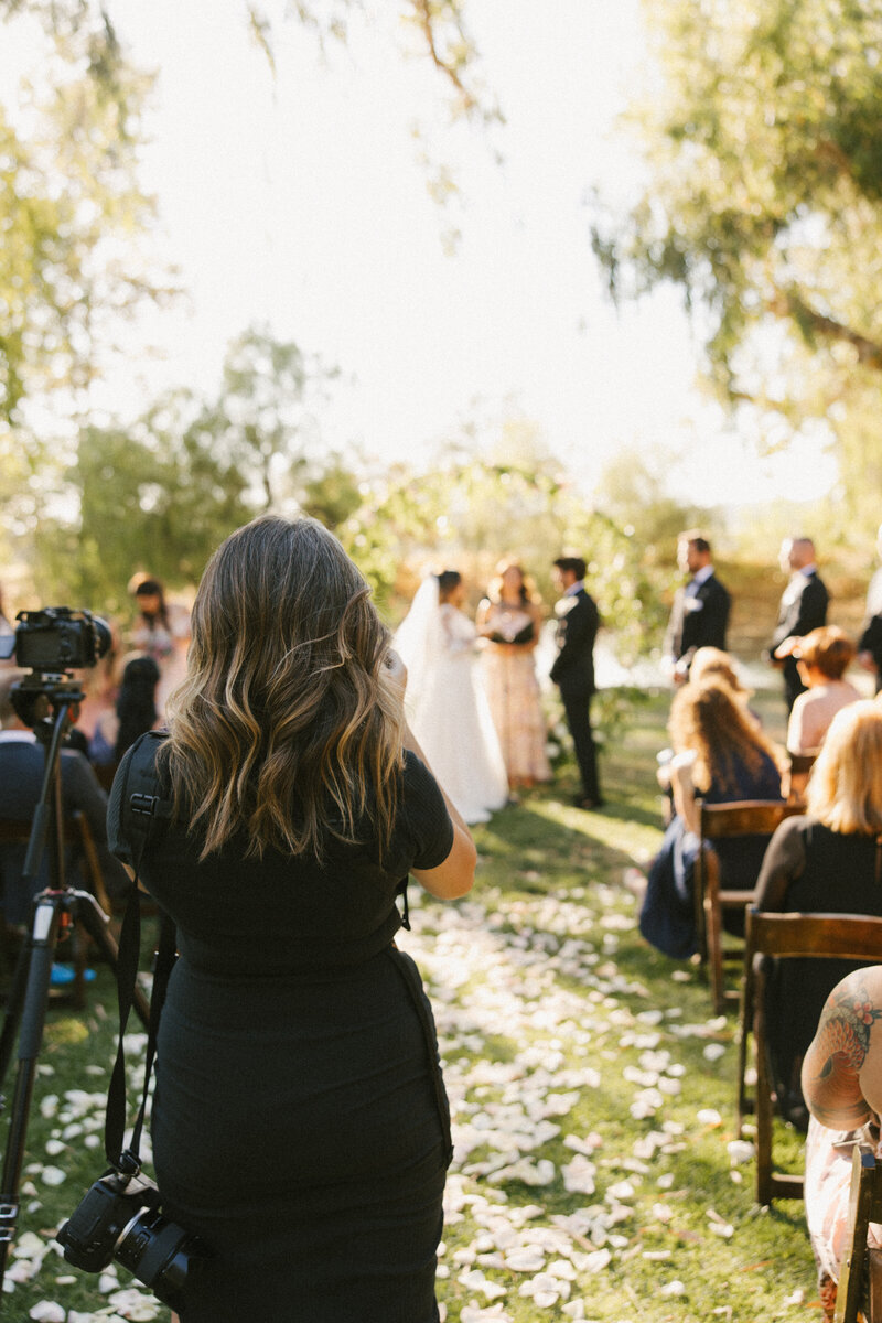 A wedding photographer in action, capturing a couple’s special moments. Her journey through California, New York, New Jersey, and even a village in England has shaped her passion for storytelling and connection.