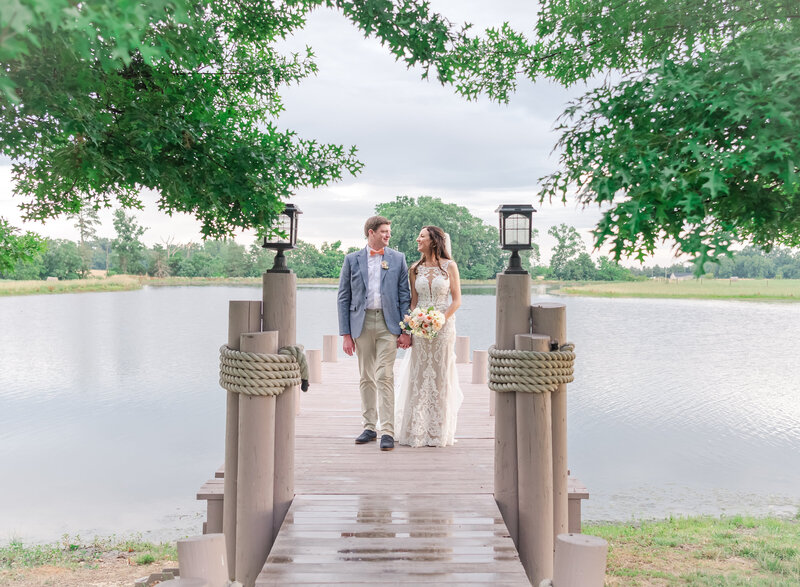 bride and groom looking at each other standing on a pier