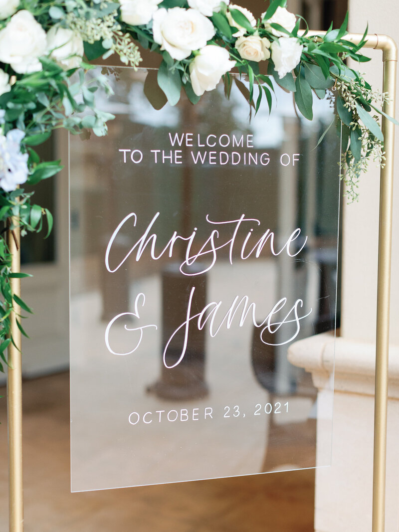 Clear acrylic welcome sign hanging on gold stand
