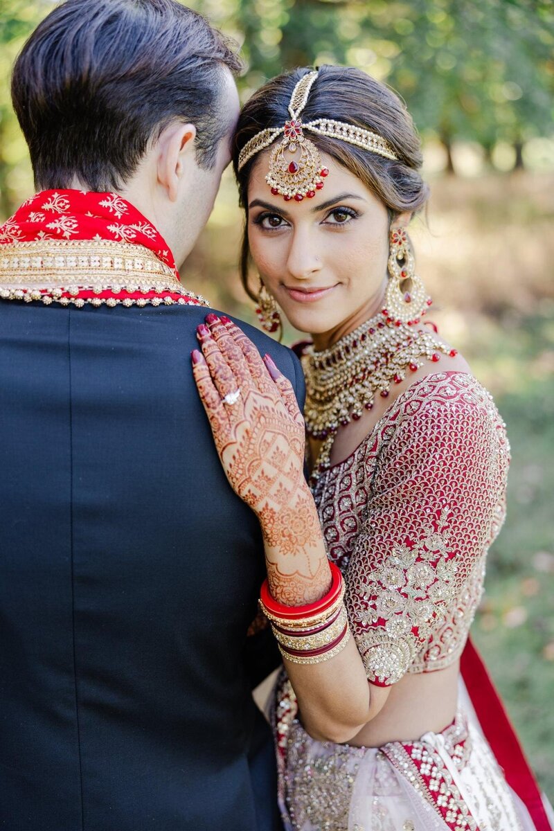 Indian bride wearing traditional garments and headpiece with henna tattoos.