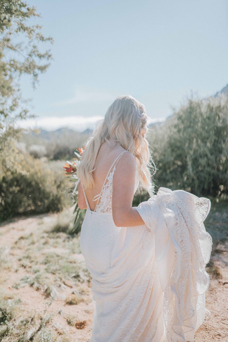 boho bride holding skirt of wedding dress walking through the desert after southern wedding in knoxville tennessee summer wedding