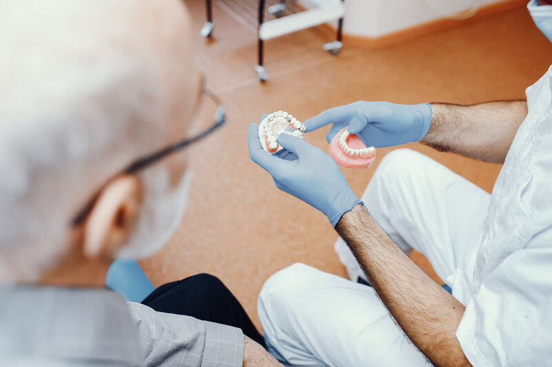 a dentist showing a patient the new set of dentures