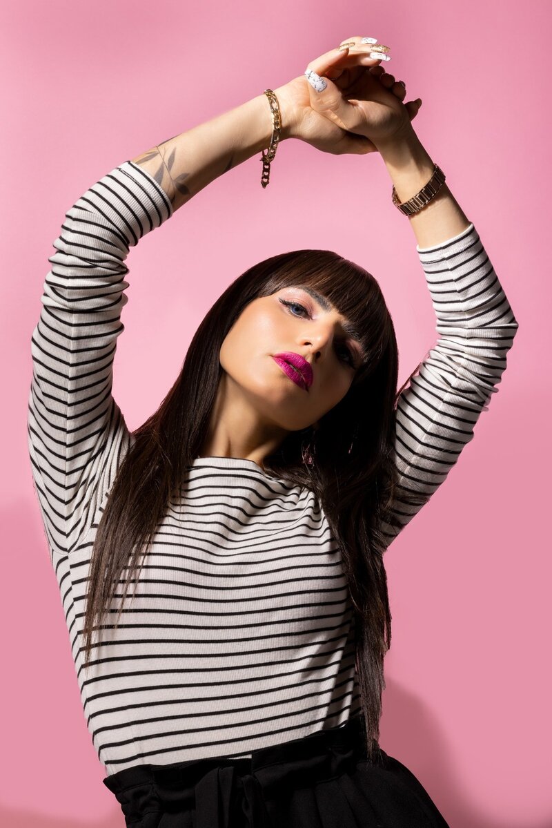 Woman in black and white stripes with pink background